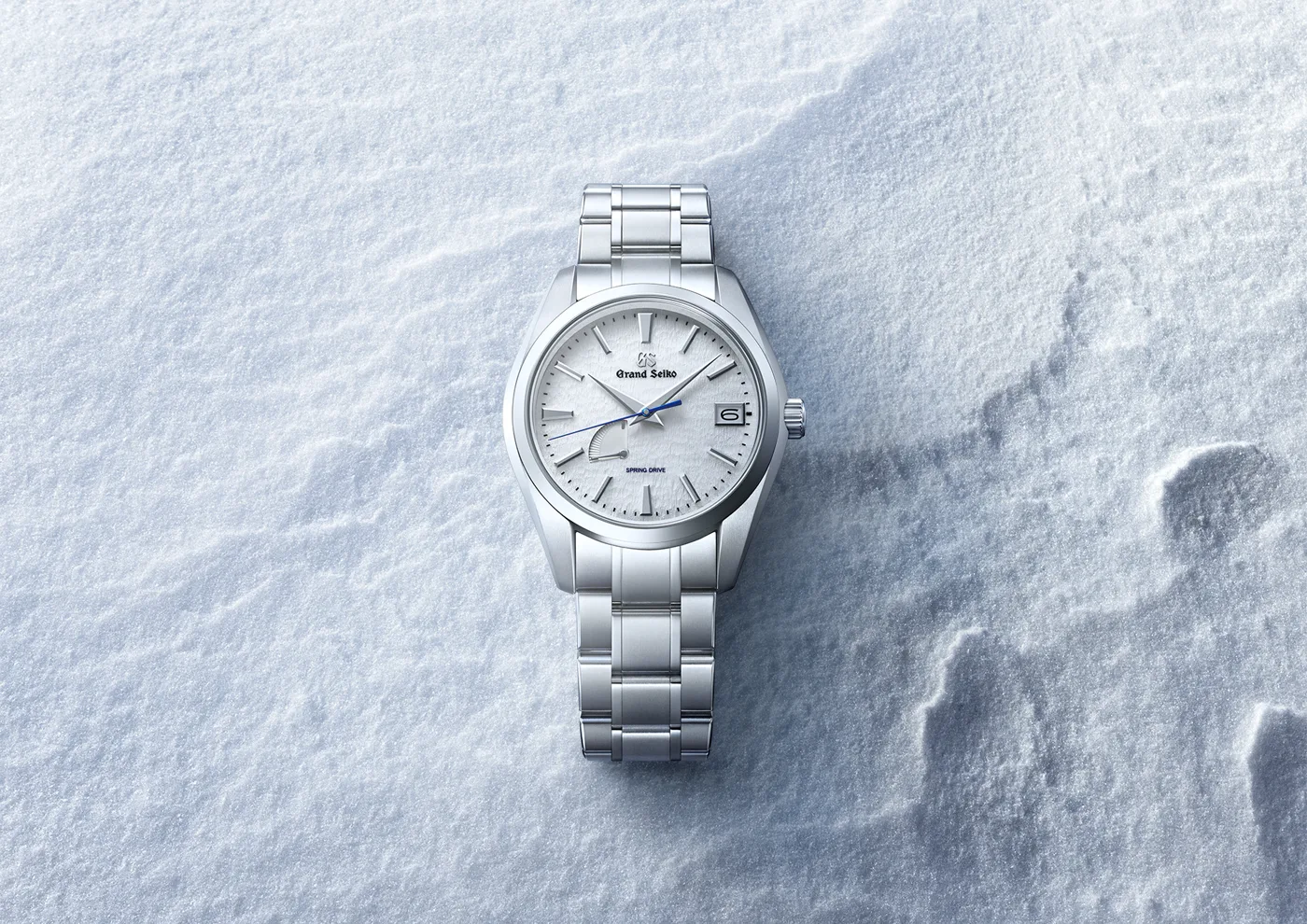 Grand Seiko Snowflake watch with white textured dial on snow, metal bracelet